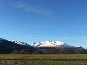 a snow covered mountain in the distance with a field at Buzzards Nest Cottage in Roybridge +7 photos