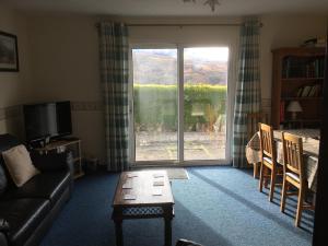 a living room with a couch and a tv at Buzzards Nest Cottage in Roybridge