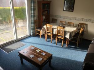 a living room with a table and chairs and a table and a tableearcher at Buzzards Nest Cottage in Roybridge