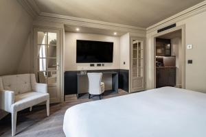 a bedroom with a bed and a desk and a tv at Hôtel Villa d'Estrées - Saint-Germain in Paris