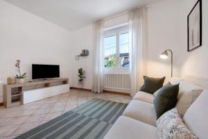 a living room with a white couch and a tv at Maddy's House in Mandello del Lario