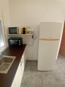 a small kitchen with a white refrigerator and a sink at COSTACABANA Apartamento in Almería