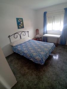 a bedroom with a bed with a blue comforter and a window at COSTACABANA Apartamento in Almería