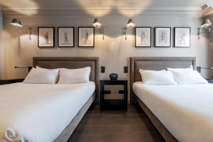 two beds in a room with pictures on the wall at Hôtel Villa d'Estrées - Saint-Germain in Paris
