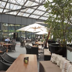 a restaurant with tables and chairs and an umbrella at Sheraton Berlin Grand Hotel Esplanade in Berlin