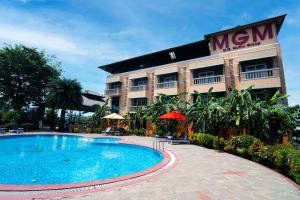a hotel with a swimming pool in front of a building at MGM Vailankanni in Velankanni