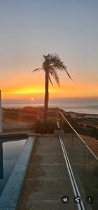 a palm tree and a swimming pool with a sunset at Exclusive luxury villa private pool and garden mnar in Tangier