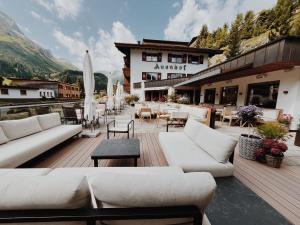 a patio with white couches and tables and chairs at Hotel Auenhof in Lech am Arlberg