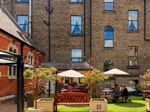 a brick building with people sitting on benches in a courtyard at Gardiner House Hostel in Dublin