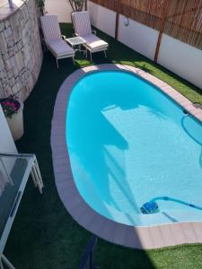 a large swimming pool with two chairs next to it at Ocean View living in Hermanus