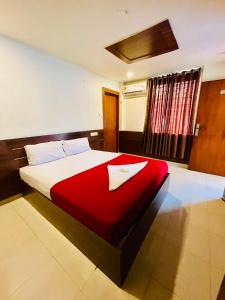 a bedroom with a large bed with a red blanket at Meridian Residency in Ernakulam