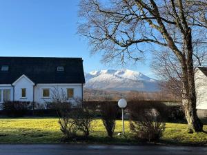 a white house with a snow covered mountain in the background at Corrie View in Roybridge