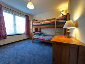 a room with two bunk beds and a desk with a lamp at Corrie View in Roybridge