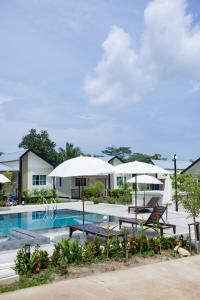 a resort pool with umbrellas and chairs at NaraRin Phuket Resorts in Thalang
