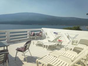 a group of chairs and tables on a deck next to the water at Džodžo Apartments in Đenovići