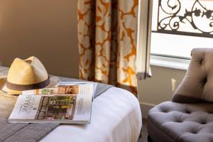 a hat sitting on top of a bed with a book at Hôtel Le Relais Saint Charles in Paris