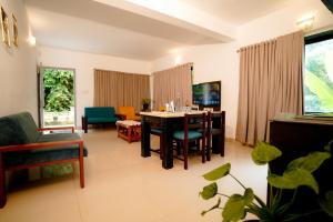 a living room with a dining room table and chairs at Veu Munnar Retreat - Valley View Rooms in Munnar