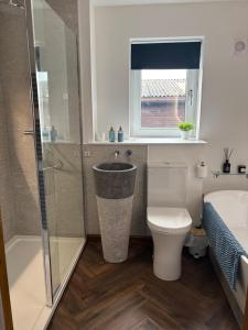 a bathroom with a shower and a toilet and a sink at Swallows Lodge in Bathgate +16 photos