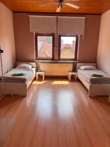 a room with two beds and two windows at Emmerstedt - Alte Schule in Helmstedt