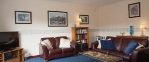 a living room with two couches and a tv at Eagles Ledge Cottage in Roybridge