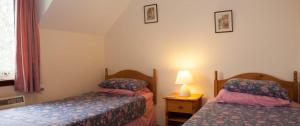 a small room with two beds and a lamp at Eagles Ledge Cottage in Roybridge