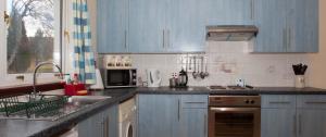 a kitchen with blue cabinets and a sink at Eagles Ledge Cottage in Roybridge +2 photos