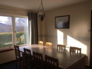 a dining room table with chairs and a large window at Eagles Ledge Cottage in Roybridge
