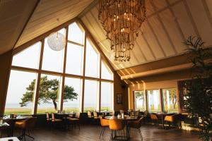 a dining room with tables and chairs and windows at Barsebäck Resort Hotell in Löddeköpinge