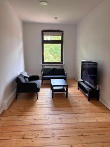 a living room with two couches and a flat screen tv at Emmerstedt - Alte Schule in Helmstedt