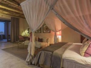 a bedroom with a canopy bed and a living room at Onguma The Fort in Namutoni Gate