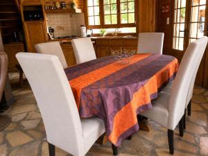a dining room table with white chairs and an orange and purple table cloth at Le coin de paradis in Bouvellemont +10 photos