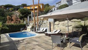 a pool with chairs and an umbrella next to a building at Opening Doors Premiá Dalt Amazing views w pool in Premia de Dalt