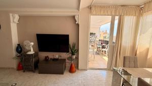 a living room with a television and a balcony at Pasión Junto al mar in Calpe