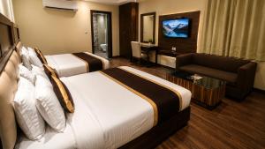 a hotel room with two beds and a couch and a television at Tulip Tree Hotel in Katra