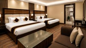 a hotel room with two beds and a couch at Tulip Tree Hotel in Katra