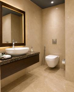 a bathroom with a sink and a toilet and a mirror at Tulip Tree Hotel in Katra