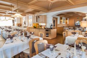 a restaurant with white tables and chairs and a kitchen at Hotel Else in Selva di Val Gardena