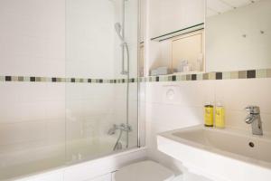 a white bathroom with a shower and a tub and a sink at Hôtel Le Relais Saint Charles in Paris