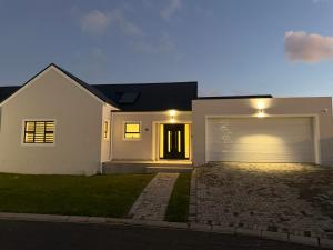 a white house with a garage at night at Hermanus Villa in Hermanus