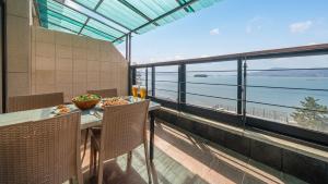a balcony with a table and chairs and a view of the ocean at Sacheon Bichae Pension in Sacheon +4 photos