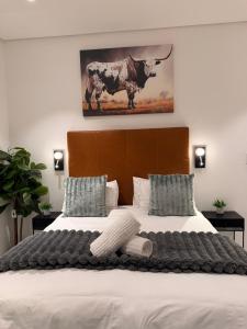 a bedroom with a large bed with a cow picture on the wall at Hermanus Villa in Hermanus