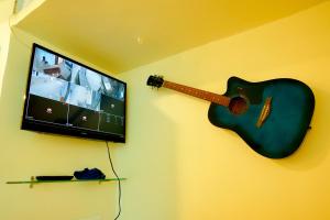 a guitar hanging on a wall with a tv at The Casa Comforts in New Hampi