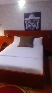 a bedroom with a white bed with a wooden headboard at October 1st Hotel in Ibadan +5 photos