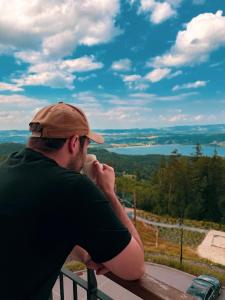 a man sitting on a bench drinking a cup of coffee at Kazalnica Family&Conference Resort by Solarento in Karpacz