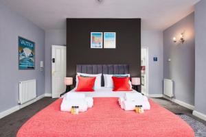 a bedroom with a large white bed with red pillows at Delven House - Self Check-in, Self-Catering Serviced Apartments in Castle Donington +120 photos
