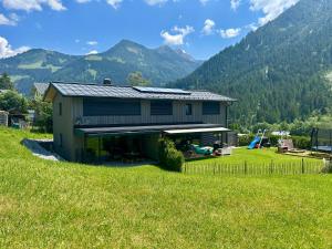 a house in a field with mountains in the background at Kracha Alpinlodge in Mittelberg