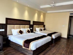 a bedroom with two beds with white sheets at Tulip Tree Hotel in Katra