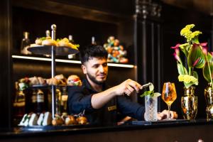 a man sitting at a bar preparing a drink at Argentum Boutique Hotel & SPA in Rome