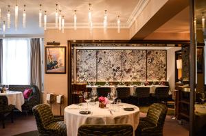 a dining room with two tables and chairs and a chandelier at Althoff St James's Hotel & Club London in London