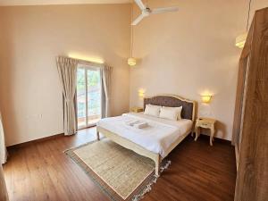 a bedroom with a large bed and a window at 3BHK Elegant Duplex Villa with Pool Access in Assagao